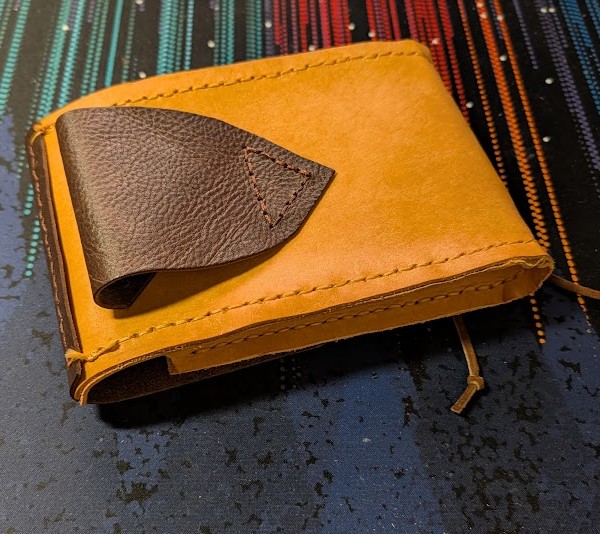 a belt pouch made of brown and tan leathers. it is flipped over showing the belt loop sewn on the back