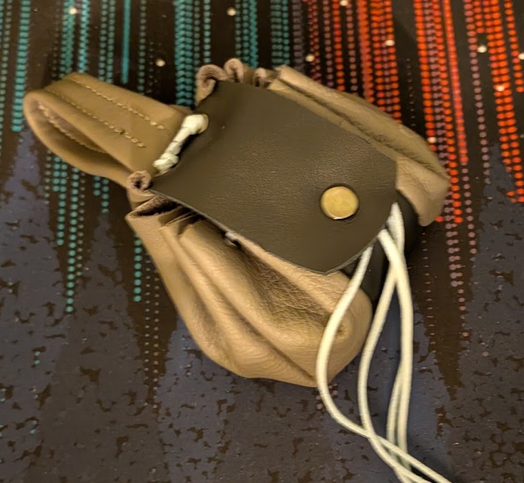 a drawstring pouch made of gray and black leathers, with a snapping cover and light blue lace