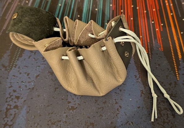 a drawstring pouch made of gray and black leathers, with a snapping cover and light blue lace